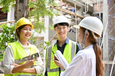 Profesyonel ve çekici bir Asyalı mimar kadın yönetici inşaat alanında iki mühendis ile harika bir konuşma yapıyor..