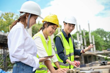 Asyalı güzel bir kadın mimar inşaat alanında inşaat mühendisi ve inşaat müfettişi ile açık havada toplantı yapıyor. İnşaat mühendisi kavramı