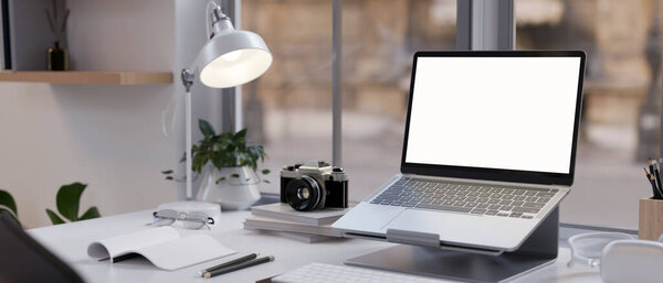 Modern office desk workspace with laptop white screen mockup is on a laptop stand, table lamp, stationery, and decor. close-up view. 3d rendering, 3d illustration