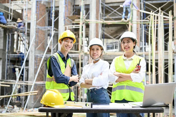 Portrait, A group of a professional Asian millennial civil engineer standing in front of the construction site with crossed arms. Civil engineer, architect, construction inspector.
