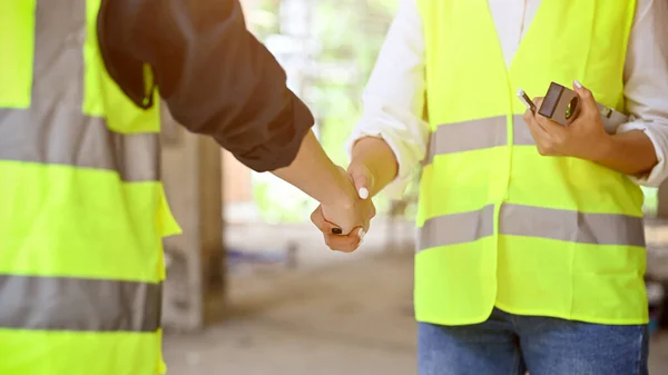 建設現場の男性建設検査官と安全均一な握手でプロの男性土木技術者 切り取られクローズアップされた画像 — ストック写真