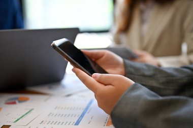 Ekibiyle toplantıdayken internetten bilgi aramak için akıllı telefonunu kullanan bir iş kadını. kırpılmış ve yakın plan resim