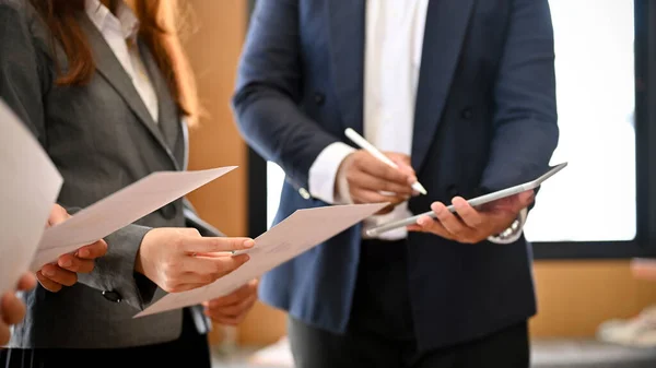 A professional businesspeople in formal suit are in the meeting with their boss, reading a meeting information on the paper. cropped image