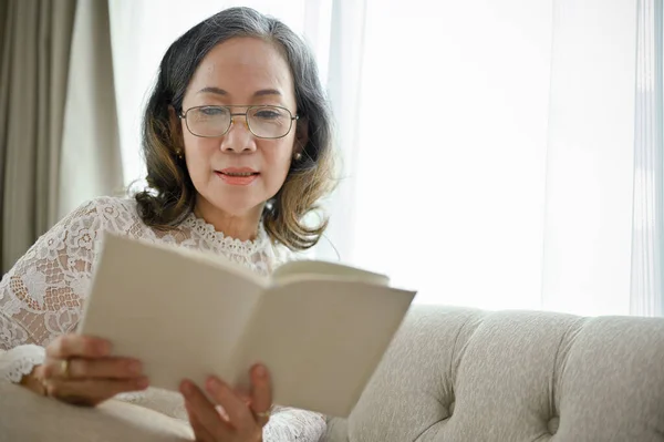 Klidná Uvolněná Žena Asijského Věku Brýlích Soustředí Čtení Knihy Svém — Stock fotografie