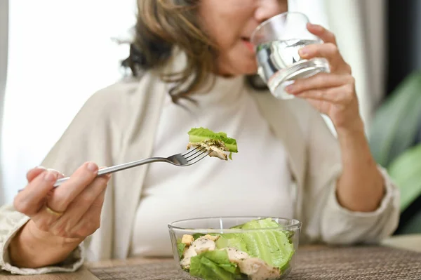 健康快乐的亚裔老人在她的饭厅里吃沙拉碗和喝水 剪裁后的特写图像 — 图库照片