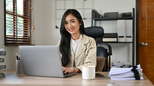 魅力的で美しい千年のアジアのビジネスマンや女性の上司は オフィスにあり 彼女のオフィスの机に座って 笑顔とカメラを見ています — ストック写真