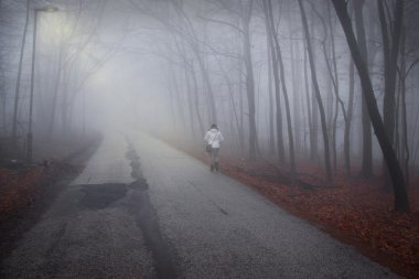 kadın sisli orman yolu üzerinde yürüyor