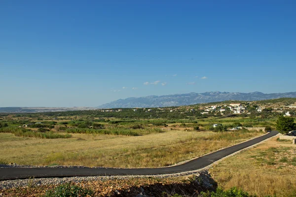 Üres island road, kis falu és a kék hegyek — Stock Fotó