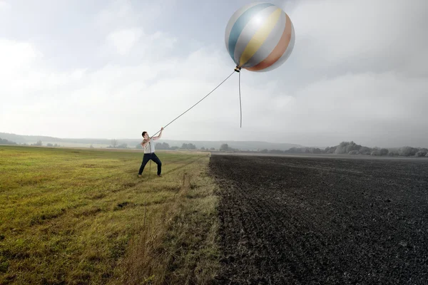 Homem está puxando um balão em Grassfield — Fotografia de Stock