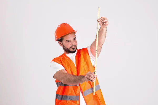 Trabajador de la construcción en casco de seguridad está midiendo con medidor — Foto de Stock