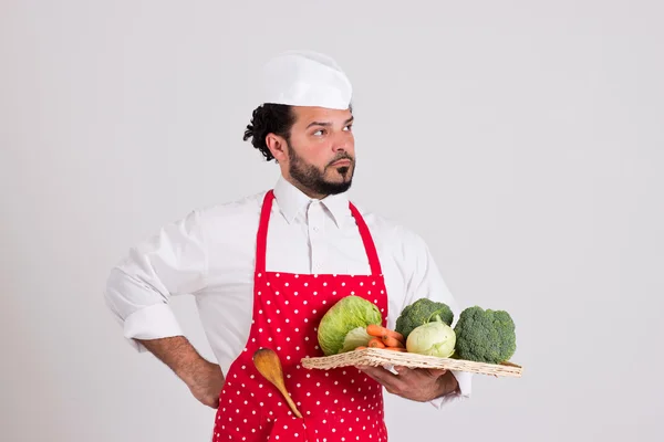 Jefe de cocina italiano en delantal rojo está sosteniendo bandeja de mimbre con verduras —  Fotos de Stock