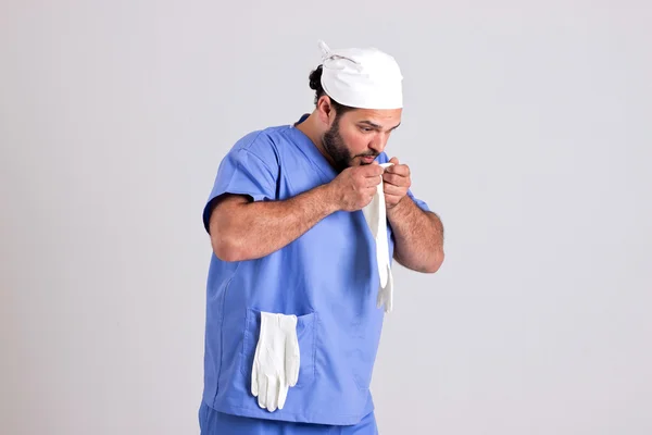 Joven doctor en traje clínico sopla a guante de cirugía —  Fotos de Stock