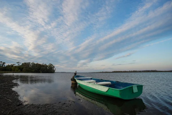 一条绿色的小船停泊在湖边 船是空的 没有人在里面 天空在水中反射 — 图库照片
