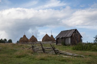 Dış binaların yakınındaki saman yığınları kasvetli bir gökyüzüne karşı.
