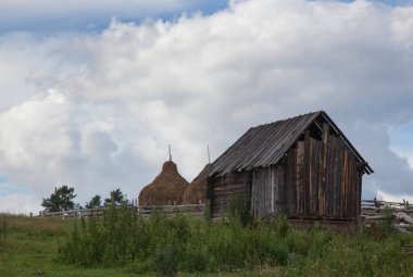 Dış binaların yakınındaki saman yığınları kasvetli bir gökyüzüne karşı.