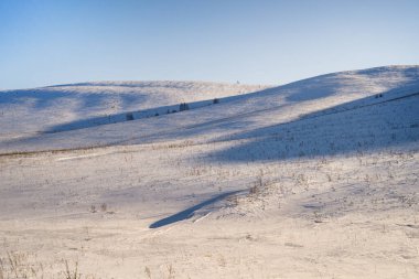 Parlak bir kış masmavi gökyüzünün altında tepeleri olan beyaz karlı bir arazi.,