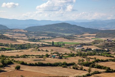 Hasattan sonra tepelik bir alanda tarım arazileri. Nadir ağaçlar. Yüksek görüş açısı. Uzakta yüksek dağlar.