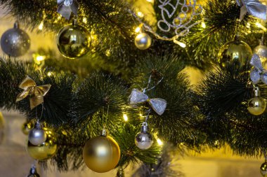 Işıklı çelenklerin aydınlatılmasında Noel kompozisyonu. Mücevherli Noel ağacı, çok renkli yaylar, hayvanlar, çanlar, parlayan ışıklar. Tatil konsepti. Seçici odak ile yakın plan