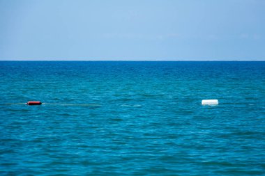 Denizde kırmızı ve beyaz güvenlik şamandıraları, sahildeki yüzme alanının çitleri. Seçici odak