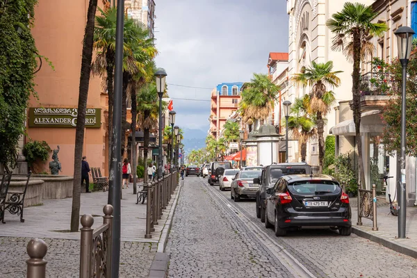Batumi, Georgia Eylül 2021: Eski şehrin sokakları, taştan yapılmış bir yol, park edilmiş arabalar, kaldırımlar boyunca palmiye ağaçları ve sokak direkleri, arka planda gri bir gökyüzü ve dağlar 