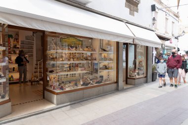 GIRONA, İSPAIN - 4 Nisan 2021: Bir ayakkabı mağazasının vitrini ve covid-19 salgını sırasında insanların yüz maskesi takarak yürümesi