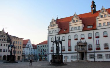 Rönesans Tarihi Belediye Binası, 1541 'de tamamlandı, Pazar Meydanı' nda, Martin Luther heykeli önde, günbatımı gölgeleri, Lutherstadt Wittenberg, Almanya - 23 Eylül 2007