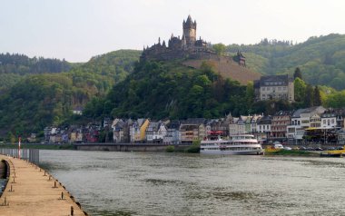 Moselle River, with hilltop Imperial Castle overlooking the town and surrounding landscape, view from the concrete mooring pier on the opposite bank, Cochem, Germany - May 4, 2022