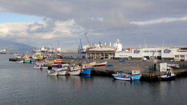 Small colorful fishing boats moored at the pier of the fishing port in the harbor, sunset golden hour view, Ponta Delgada, Sao Miguel, Azores, Portugal - July 30, 2022
