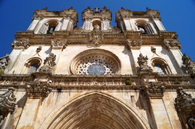 Alcobaca Monastery, portal and rose window of the church are original early 13th century Gothic, while the towers are 18th century Baroque, details of the facade, Alcobaca, Portugal - August 8, 2016