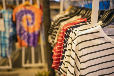 Yazın giyilecek gömlek ve giysiler tasarımcı giyim mağazasının rafında asılı duruyor.