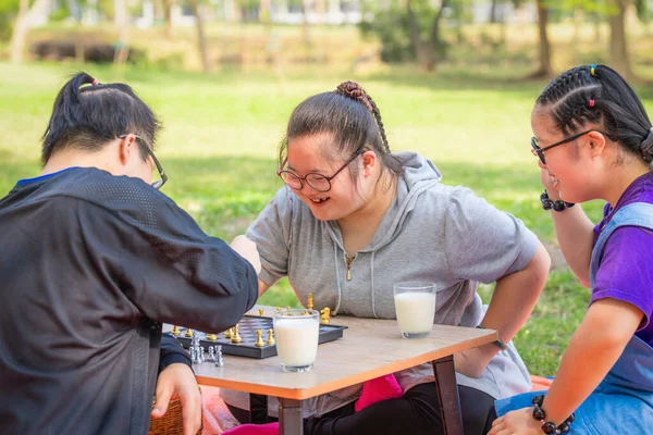 group of friends with down syndrome having fun playng chess board together outdoor in park