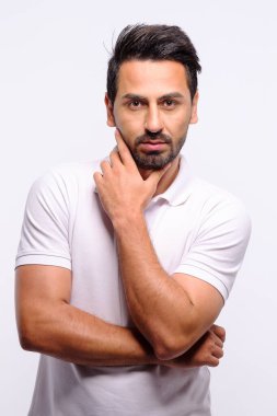 Beyaz gömlekli beyaz adam portresi ve beyaz arka planda stüdyoda kameraya bakan mavi kot.