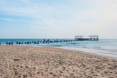 Mavi deniz ve gökyüzü üzerinde terk edilmiş bir harabe olan sahilin manzarası.