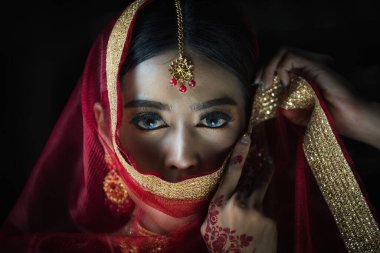 Stüdyoda, geleneksel Hint kostümlü Asyalı bir kadının kamera karşısında çekilmiş portresi.