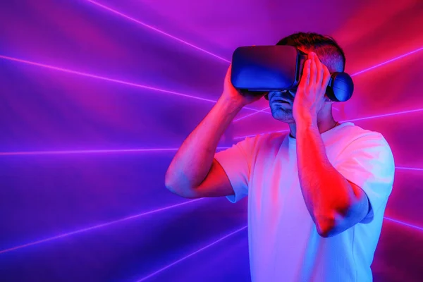 studio portrait of caucasian man using 3D virtual reality headset going into cyberspace playing video game with neon light background. Concept of virtual reality world of cysberspace and metaverse