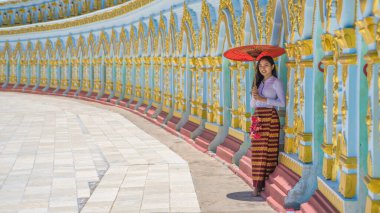 portrait of Myanmar woman in traditional dress holding umbrella standing at Umin Thonze Pagoda Sagaing hill Mandalay Myanmar