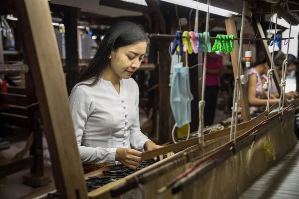 local Amarapura woman weaving hand-made tradional myanmar fabric at weaving factoryin Mandalay Myanmar