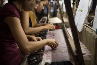 Amarapura, Mandalay, Myanmar, July 2022 - local Amarapura woman weaving hand-made tradional myanmar fabric at weaving factory