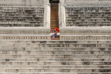 minimal portrait of Myanmar woman with red umbrella in burmese traditional dress standing at ancient pond for Buddhism worship at Maha Sandar Mahi or Muni Pagoda Amarapura Mandalay