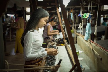 local Amarapura woman weaving hand-made tradional myanmar fabric at weaving factoryin Mandalay Myanmar