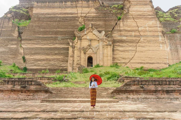portrait of Myanmar woman in traditional dress holding umbrella standing at Mingun Pahtodawgyi pagoda Manndalay Myanmar
