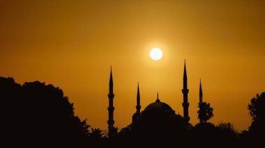 Kubbeli siluet İslami cami manzarası ve gündoğumunun arka planında iki kule.