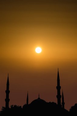 Kubbeli siluet İslami cami manzarası ve gündoğumunun arka planında iki kule.
