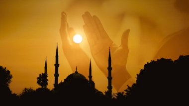 Silüet İslami camiinin arka planında, gündoğumunun arka planında Müslümanların ellerine tapan ve Allah 'a dua eden gökyüzü var. Kutsal Ramazan 'ı kutlamak için İslami arka plan