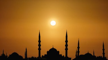 Kubbeleri ve arka planda gün doğumuyla ilgili kuleleri olan siluet İslami camii manzarası