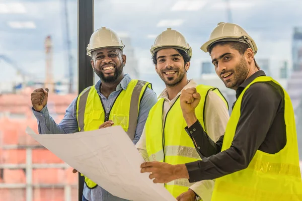 engineering industry and business background of three civil engineer standing together raise fist up to show teamwork and confident for project success
