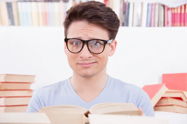 Verward student omgeven door boeken — Stockfoto