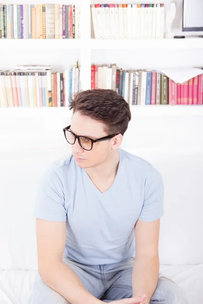 Mannen med glasögon som sitter på en soffa — Stockfoto