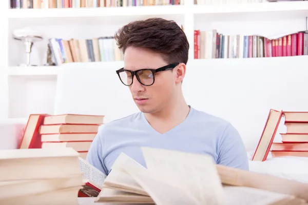 Student with glasses studying surrounded by books — Stock Photo, Image