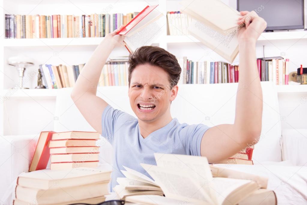 angry student surrounded by books throws books